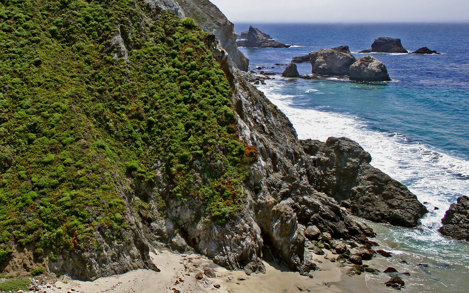 A sea shore with multiple floating rocks in the background.